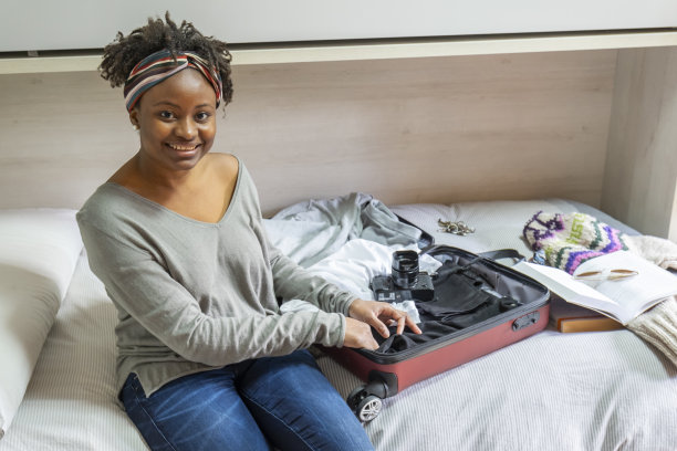 一个女人坐在床上，她的行李箱开着放在她面前图片下载