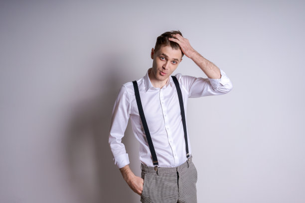 一个穿着白衬衫和背带裤的男人正在摆姿势拍照图片下载