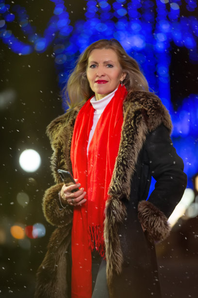 一个美丽的中年妇女的肖像在一个傍晚的冬天的城市。图片下载