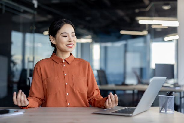 年轻的女商人在现代办公室工作时冥想和练习正念图片下载