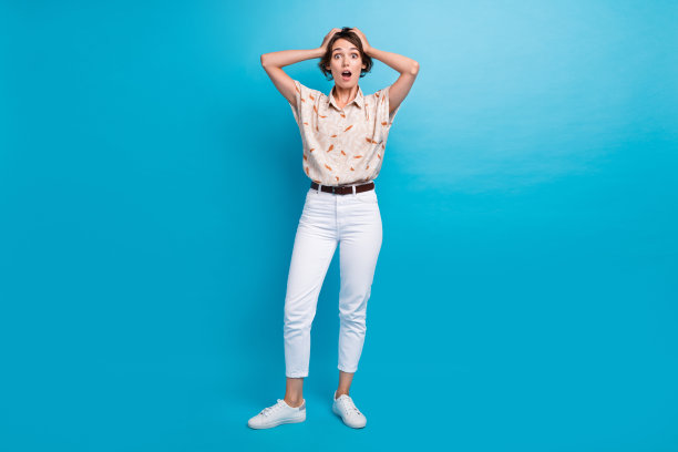 照片上的女孩穿着时髦的衣服，两只手碰着头，omg的反应孤立在蓝色的背景上图片下载