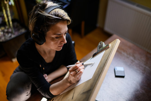 带着耳机的创意插画师在家里用铅笔画画图片下载