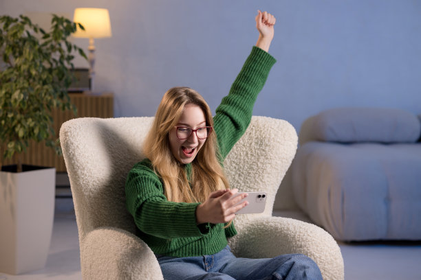 一名女子坐在椅子上，双手高举，正在使用手机图片下载