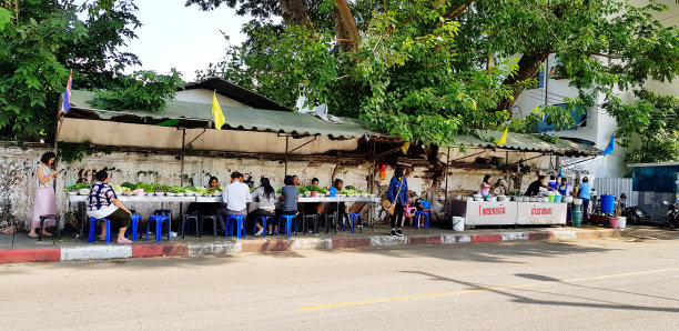 泰国曼谷Ratchaburi街头食品市场，亚洲人在有房子和大树背景的人行道上吃东西。泰国人，游客。图片下载