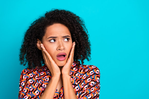 照片的少女震惊的女士穿着印花衬衫手臂脸颊看起来空白的空间孤立蓝绿色的背景图片下载