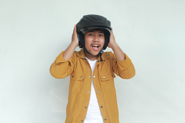 年轻的亚洲男子微笑和自信的手势，同时戴着摩托车头盔。图片下载