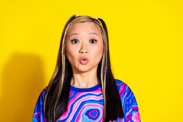 时髦的年轻日本女孩的照片，染了头发，惊讶的反应，噘起的嘴唇，在黄色的背景上实现了孤立的销售图片下载