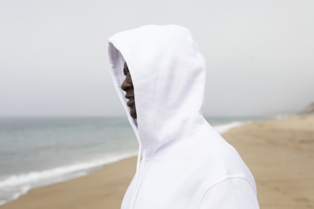 酷酷的非洲裔美国人穿着白色连帽衫在海滩拍摄冬季照片图片下载