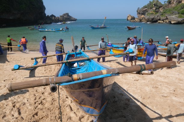 在Ngrenehan海滩上，一群渔民在公海上搜寻了一夜之后，将这艘船推向海滩。图片下载