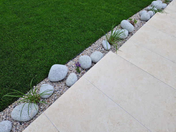 一条狭窄的花坛沿着通往房子的车道，铺着浅米色的瓷砖。砾石被水软化，铺满卵石的床图片下载