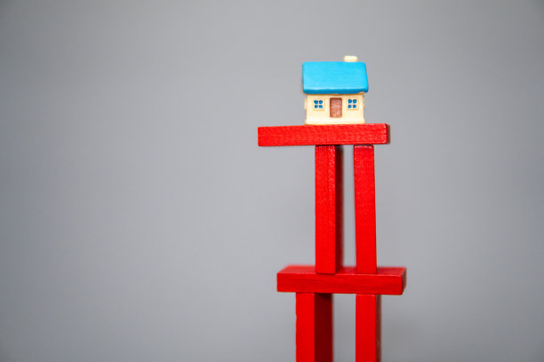 一个玩具房子的特写照片，在一堆岌岌可危的红色木块上。图片下载