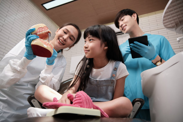 一位亚洲女牙医在牙科诊所向一个女孩展示牙刷。图片下载