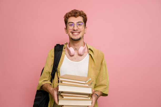 微笑的大学生拿着粉红色背景的书图片下载