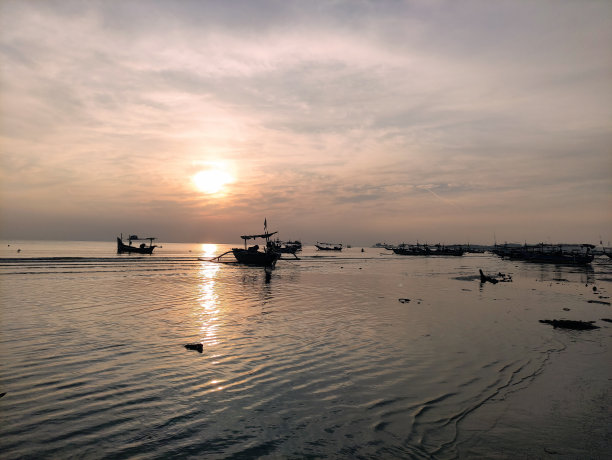 日落时停泊在海滩上的船的剪影图片下载