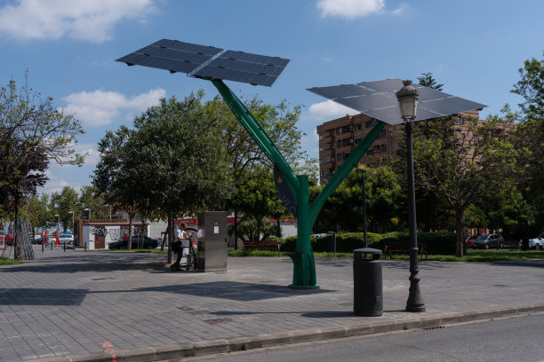 西班牙瓦伦西亚- 2024年6月13日-年轻人使用光伏树为他的免费电动滑板车充电的照片图片下载