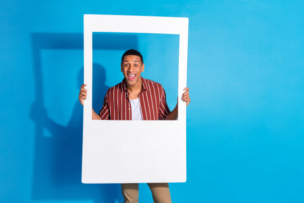 照片喜出望外的好心情的好男人穿条纹时尚衬衫在白色t恤hold相框孤立的蓝色背景图片下载