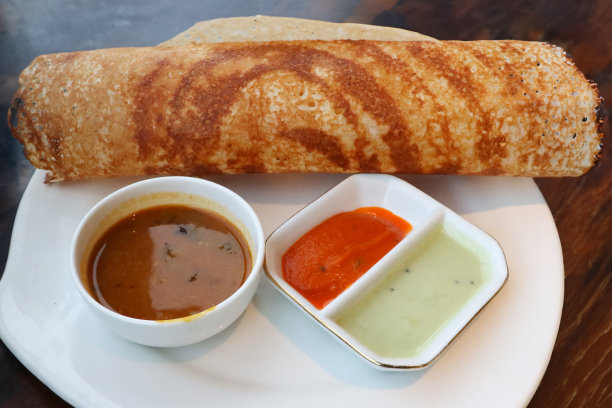 白色盘子里的特写图片，里面装着马萨拉土豆泥和切碎的洋葱，里面塞满了马萨拉土豆泥，还有调味料、椰子酸辣酱和桑巴，早餐时间，木纹背景，提升视野图片下载