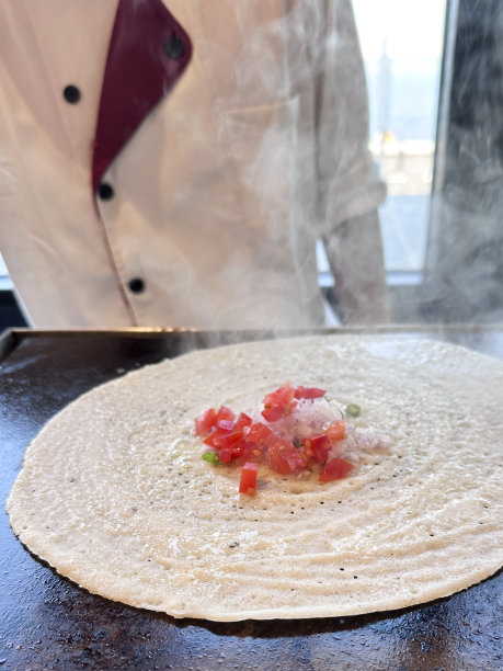 特写图片:难以辨认的厨师，身穿白色厨师服，在热炉炉板上准备玛莎拉薄饼，切碎的水果和蔬菜浇头，上升的蒸汽，商业厨房的设置，高架视图，聚焦于前景图片下载