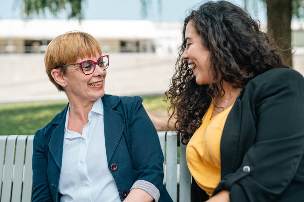 坐在城市长椅上使用智能手机的商人。分享时间，同事休息。图片下载