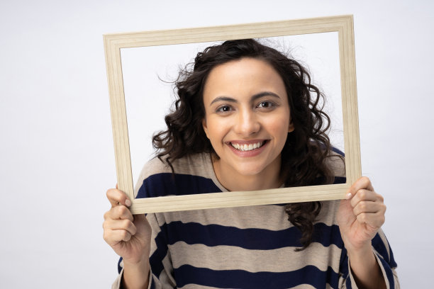 照片华丽可爱的女人卷发条纹t恤摆姿势在木相框孤立的白色背景股票照片图片下载