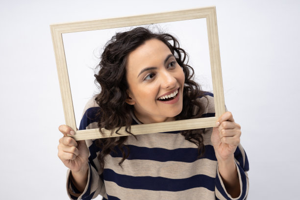 照片华丽可爱的女人卷发条纹t恤摆姿势在木相框孤立的白色背景股票照片图片下载