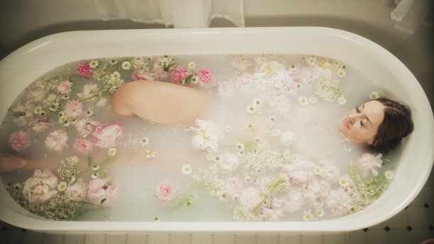 孕妇在洗澡。水疗日，在充满花瓣的水中放松，放松背背酸痛，因为带着孩子。淹没在水中图片下载