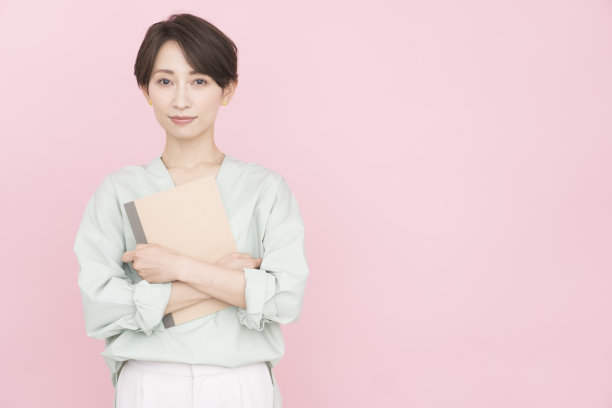 一个女人拿着笔记本，看着镜头，微笑着。图片下载