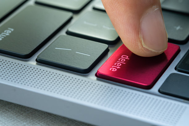 电脑用户的手指，他按下了电脑键盘上的删除键。图片下载