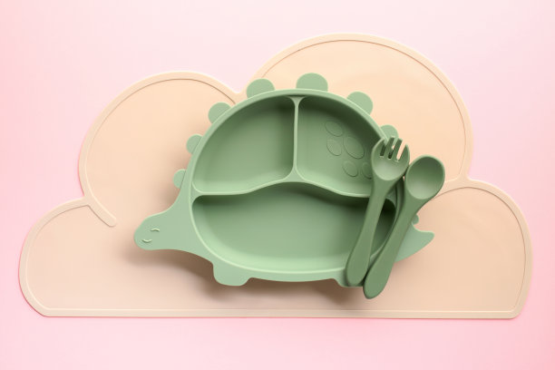 空恐龙形状的儿童餐具与配套的器皿在柔和的粉红色背景，完美的参与用餐时间。图片下载