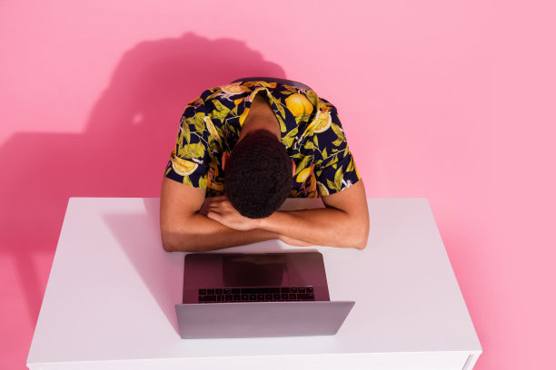 照片顶视图睡觉的家伙坐桌子与上网本孤立柔和的颜色背景图片下载