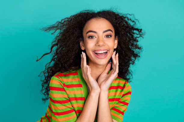 照片肖像可爱的年轻女士飘动的头发微笑穿着时尚的条纹服装孤立的青色背景图片下载