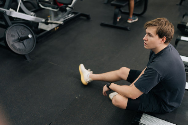 从高角度看疲惫的跑步者在健身房休息，坐在跑步机上。筋疲力尽、汗流浃背的男性在有氧运动后呼吸困难的照片图片下载