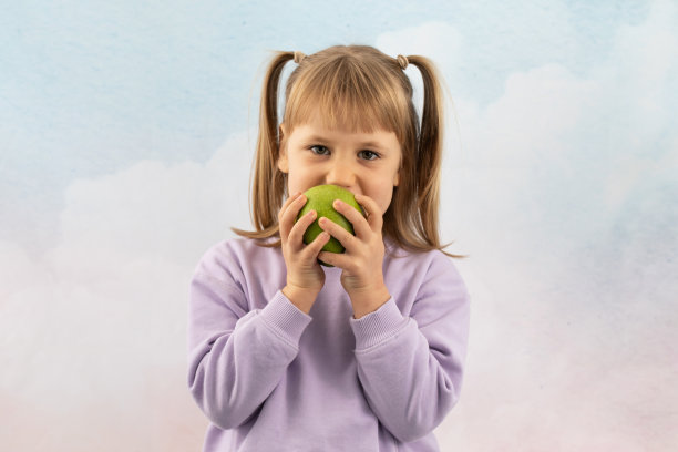 年轻的女士愉快地吃着从花园里摘来的新鲜苹果当点心图片下载