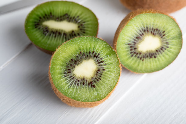 一个特写图像，新鲜的，半猕猴桃在一个白色的木制表面。图片下载