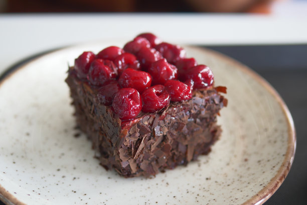 在一张特写照片中，白色盘子上美味的巧克力蛋糕片配上樱桃图片下载