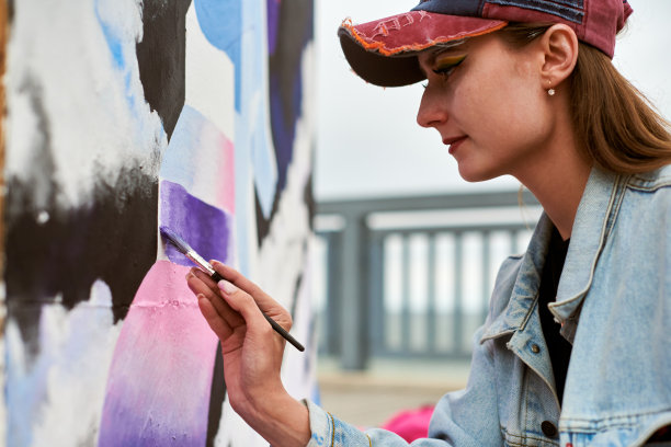 女画家用画笔在帆布上作画，准备参加户外街头展览图片下载