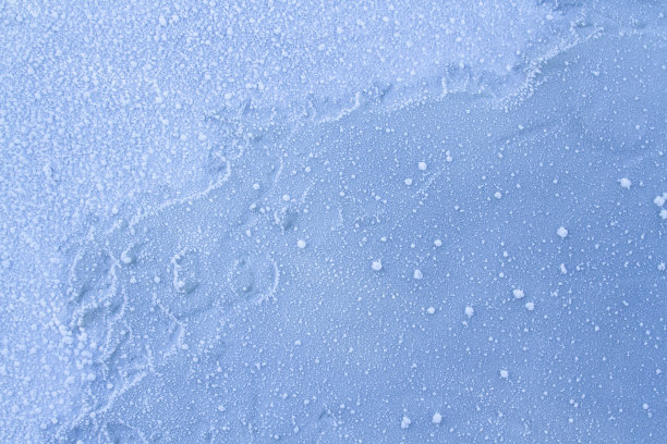 近距离的详细照片，雪和冰冻的水滴坐落在冰冻的蓝色冰层上。图片下载