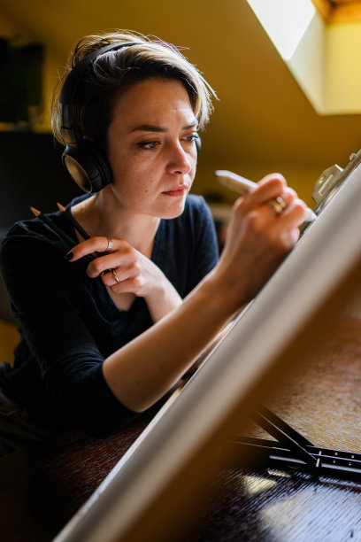 肖像专注的艺术家与耳机素描在舒适的家。图片下载