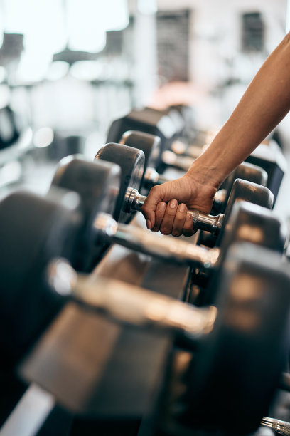 在健身房，一只女性的手拿着一个沉重的哑铃的特写照片。图片下载