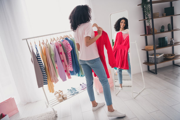 照片中迷人可爱的漂亮女孩选择时髦的公寓衣柜里的衣服图片下载