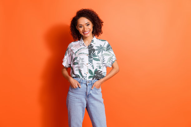 迷人的模特女孩的照片肖像，穿着牛仔裤和时尚的夏威夷衬衫，在黑色星期五的季节销售中摆姿势，孤立的橙色背景图片下载