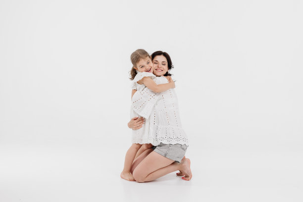 一位穿着浅色衣服的母亲正在和一个可爱的小女孩玩得很开心。母亲和小女儿被隔离在白色背景上。母亲节，爱，家庭，亲子，童年的概念。图片下载