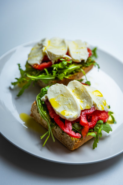 健康素食三明治与马苏里拉奶酪，香蒜酱，芝麻菜，牛排番茄，淋上橄榄油，酵母面包。美丽的自然光-股票照片图片下载
