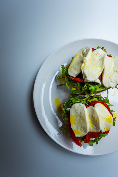 健康素食三明治与马苏里拉奶酪，香蒜酱，芝麻菜，牛排番茄，淋上橄榄油，酵母面包。美丽的自然光-股票照片图片下载