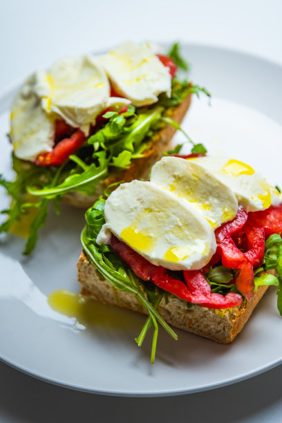 健康素食三明治与马苏里拉奶酪，香蒜酱，芝麻菜，牛排番茄，淋上橄榄油，酵母面包。美丽的自然光-股票照片图片下载