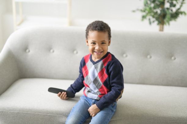 男孩坐在家里的沙发上看电视图片下载