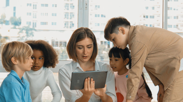 老师拿着平板电脑向一群学生开放在线课程。博学。图片下载