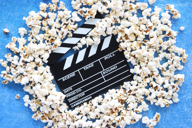 图片中黑色的隔板被洒出的爆玉米粒包围，打开的铰链隔板，斑驳的蓝色背景，抬高的视角图片下载