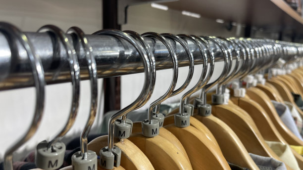 挂在木制衣架上的收货架上的特写，浅色背景上有XXS、XS、S、M、L、XL、XXL的塑料尺寸标签图片下载