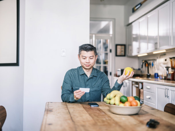 年轻的亚洲男子在家里检查他的健康保险卡图片下载